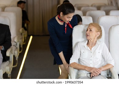 Air Hostess Talking With Senior Passengers On Airplane