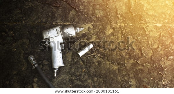 Air\
impact wrench and air hoses, as well as an impact socket on the\
ancient rock floor with a sunlight and copy\
space
