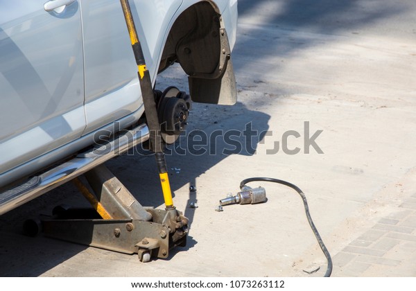 Air impact wrench on the ground, close-up\
image, near the car with the wheel\
removed