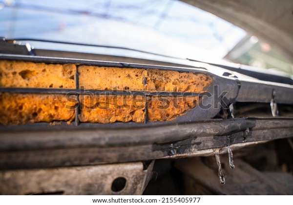 The air intake of the car is foamed with orange\
mounting foam, close-up. Broken car air conditioner, non-working\
stove