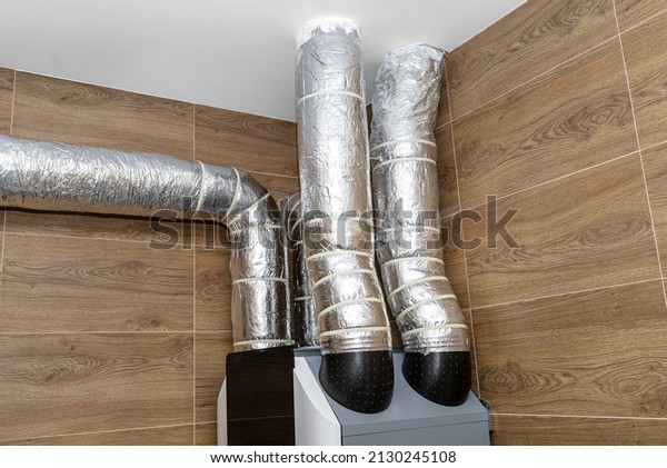 Air intake and exhaust in the home mechanical\
ventilation with heat recovery with visible insulated pipes with\
silver foil entering the\
ceiling.