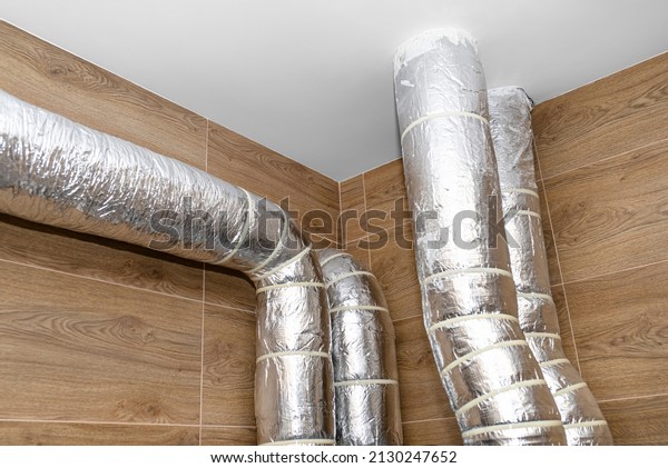 Air intake and exhaust in the home mechanical\
ventilation with heat recovery with visible insulated pipes with\
silver foil entering the\
ceiling.
