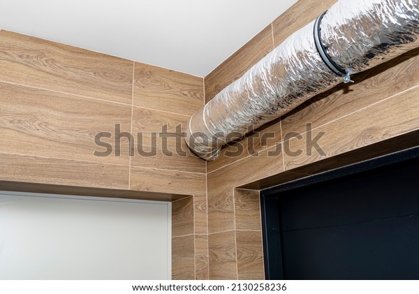 Air intake and exhaust in the home mechanical\
ventilation with heat recovery with visible insulated pipes with\
silver foil entering the\
wall.