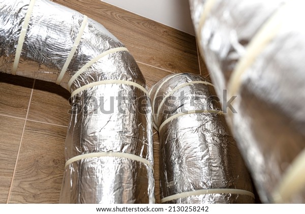 Air intake and exhaust in the home mechanical\
ventilation with heat recovery with visible insulated pipes with\
silver foil entering the\
wall.