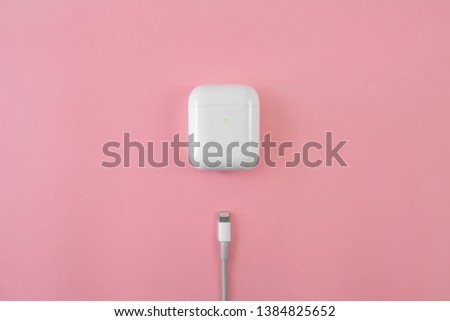 Air Pods. with Wireless Charging Case. New Airpods 2019 on pink background. Airpods. female headphones. Lightning to USB Cable