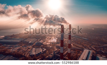 Air pollution by smoke coming out of two factory chimneys. Industrial zone in the city. Kiev, Ukraine, aerial view