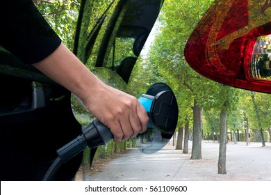 Air Pollution And Reduce Greenhouse Gas Emissions Concept. Double Exposure Of Hand Holding And Charging Electric Car With The Power Cable Supply Plugged In With Green Nature View.  