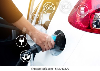 Air Pollution And Reduce Greenhouse Gas Emissions Concept. Hand Holding Electric Charging Vehicle Car And Icons With Blur Cars Background.