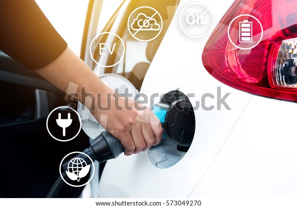 Air pollution and reduce greenhouse gas\
emissions concept. Hand holding Electric charging vehicle car and\
icons with blur cars\
background.