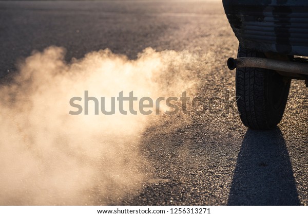 Air pollution\
from vehicle exhaust pipe on road. Pollution of environment by\
combustible gas of car. 