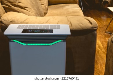 An Air Purifier With HEPA Filter And UV Lamp Placed By The Side Of A Sofa Chair In The Living Room.