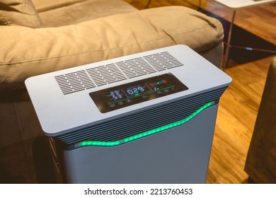 An Air Purifier With HEPA Filter And UV Lamp Placed By The Side Of A Sofa Chair In The Living Room.