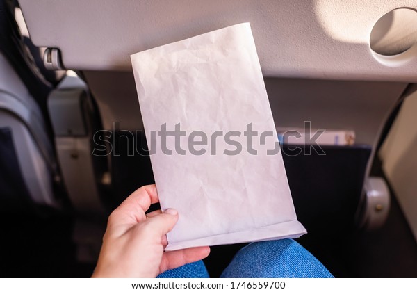 Air sickness paper bag in the hand of\
nauseous passenger during flight in the airplane.\
