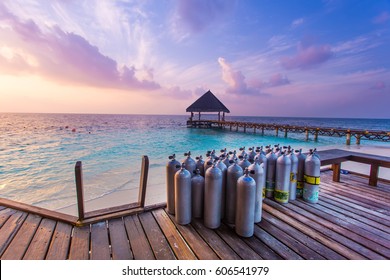 Air Tanks for Scuba Diving in a wooden platform near the diving club Maldives white sand beach. Beautiful sunset.