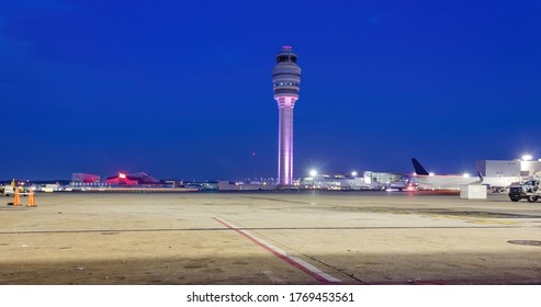 Air Traffic Control Tower After With Fueling Trucks On A Soft Blue Night Sky.