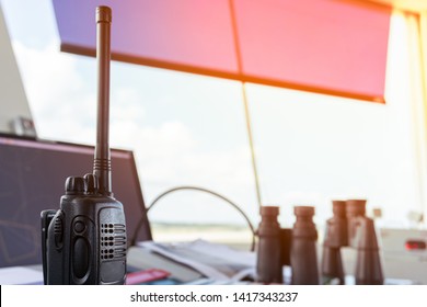 Air Traffic Controller Using Mobile Radio Pushing Push To Talk (PTT) Button To Transmit Message To Aerodrome Traffic In Front Of The Desk Which There Are Flight Progress Strip And Binoculars On It