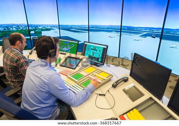 Air\
Traffic Controllers in air traffic simulator center with monitors\
and radar in the\