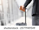 Air Travels Concept. Closeup Shot Of Man With Suitcase Holding Passport And Airline Tickets, Unrecognizable Male Traveller Waiting For Flight Boarding In Arport Terminal, Rear View, Cropped Image