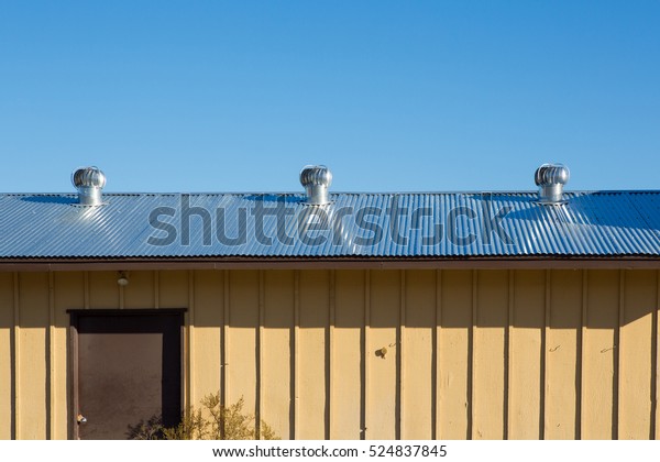 Air ventilator on the zinc roof of an office. Natural\
Roof Ventilators on the roof top spinning and take cool wind into\
the building. 