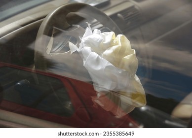 Airbag after road collision, front impact, deployed airbag on steering wheel, driver protection. Blown up airbag after car crash, road accident. 
