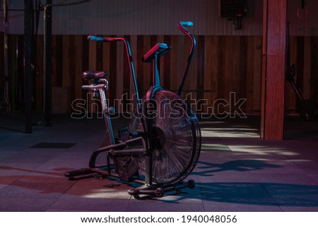 Airbike, professional exercise bike with aerodynamic loading system in red-blue neon light in a modern health class. Cross training