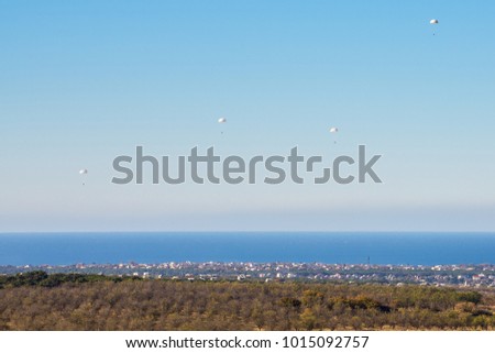 Airborne troops a mass parachute drop over the sea. On a blue sky background
