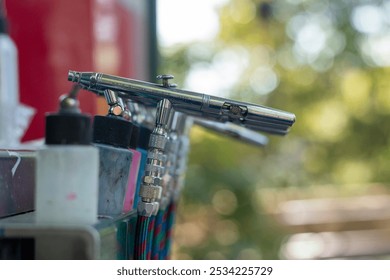 Airbrush tools lined up at a creative workspace during a sunny afternoon in a vibrant studio - Powered by Shutterstock