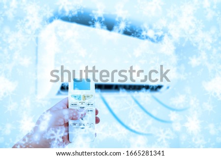 Aircondition cold blowing air concept with a person's hand holding a remote.