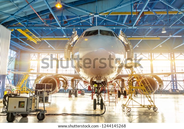 Aircraft in the aviation industrial hangar\
on maintenance, outside the gate bright\
light