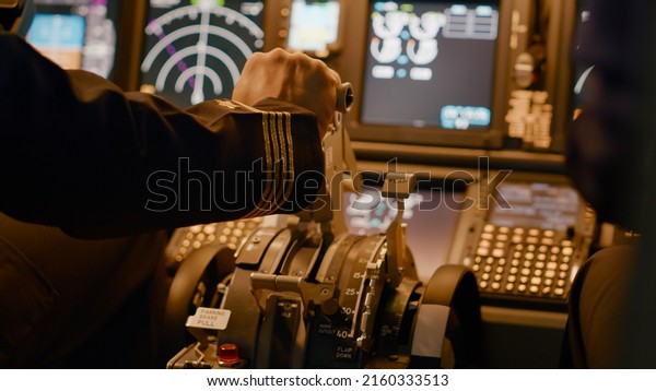 Aircraft captain in cockpit command taking off with\
airplane, throttling power engine lever to navigate radar compass.\
Airline service to fly plane with dashboard and control panel.\
Close up.