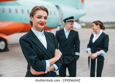 Aircraft Crew In Work Uniform Is Together Outdoors Near Plane.