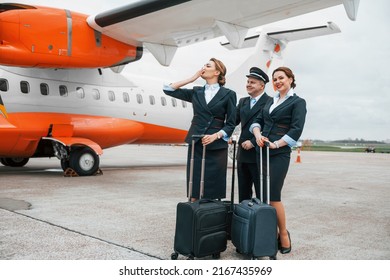 Aircraft Crew In Work Uniform Is Together Outdoors Near Plane.