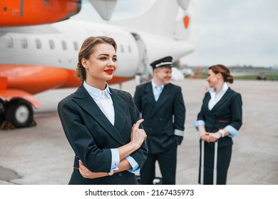 Aircraft Crew In Work Uniform Is Together Outdoors Near Plane.