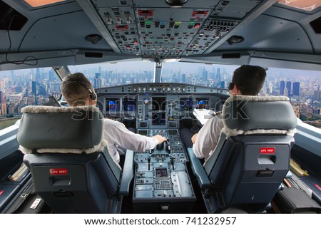 Aircraft flight deck. The pilots at work. View from airplane cockpit to the skyscrapers and city quarters.