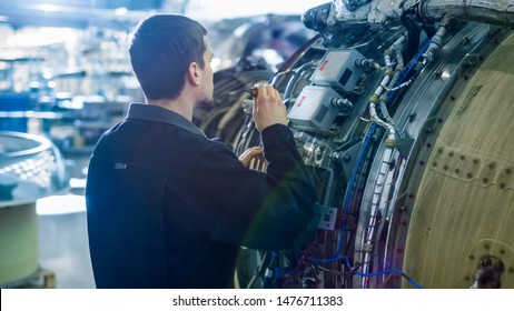 Aircraft Maintenance Mechanic Inspecting With Flashlight Airplane Jet Engine In Hangar