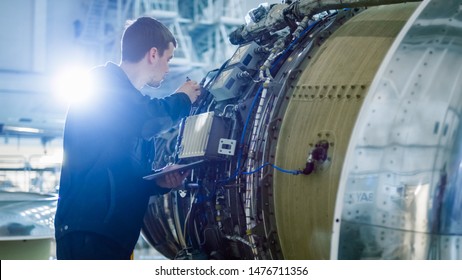 Aircraft Maintenance Mechanic Inspecting and Working on Airplane Jet Engine in Hangar