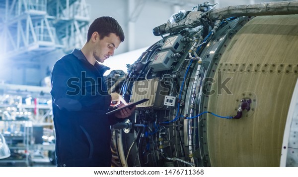 Aircraft Maintenance Mechanic Inspecting and\
Working on Airplane Jet Engine in\
Hangar