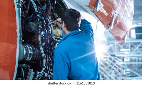 Aircraft maintenance mechanic inspects and tunes plane engine in a hangar.