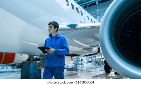 Aircraft maintenance mechanic uses tablet to inspect plane body in a hangar.