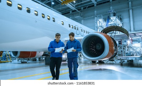 Aircraft Maintenance Mechanic Uses Tablet In Front Of A Airplane Cabin In A Hangar.