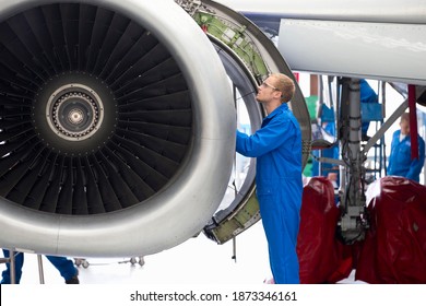 Aircraft maintenance technician checking airplane engine for safety in the airport hangar