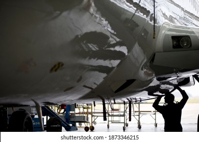 Aircraft Maintenance Technician Checking Airplane For Safety In Airport Hanger