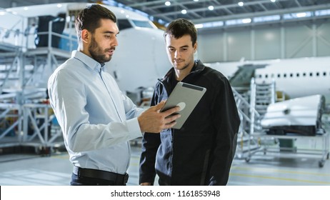 Aircraft Maintenance Worker And Engineer Having Conversation. Holding Tablet.