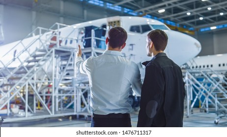Aircraft Maintenance Worker and Engineer Having Conversation. Looking at the airplane.