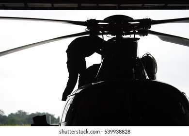 Aircraft mechanic, black and white  ,  Silhouette of a pilot arriving at the airport with a helicopter in background. Helicopter pilot in airplane hangar.

