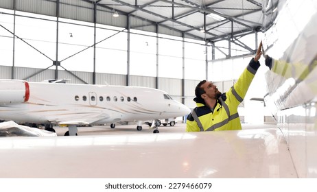 Aircraft mechanic inspects and checks the technology of a jet in a hangar at the airport  - Powered by Shutterstock