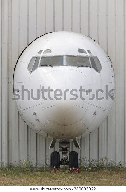 Aircraft nose in an industrial plant facade in\
vertical format