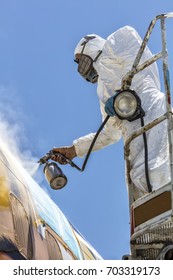 Aircraft Painting And Sandblasting.  Spray Painting, Airplane Wing. Worker In Coverall Using Airbrush. Passenger Aircraft During Maintenance And Painting.