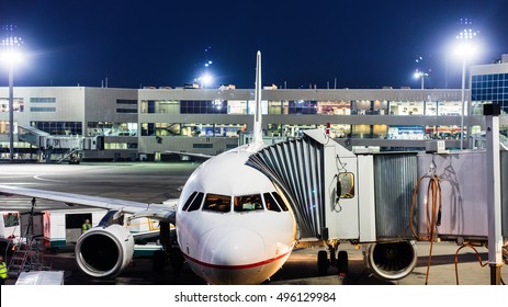 Aircraft Parked At The Airport And Preparation For Next Flight. Loading Cargo On The Plane In Airport Terminal At Night. Workers Cargo Airplane Service.