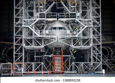  Aircraft push back into the maintenance area.Airplane parking in hangar for maintenance service check by aircraft technician.Aircraft Docking and Maintenance Platforms in front of airplane.